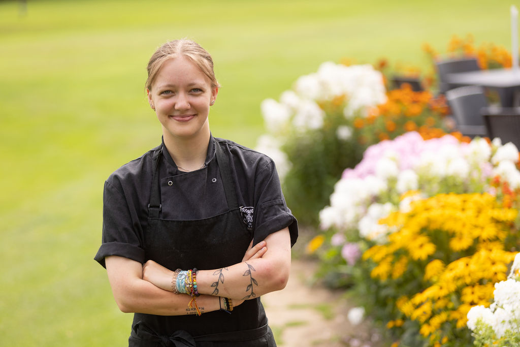 Derby College apprentice Chloe Cross stood next to a bed of flowers.