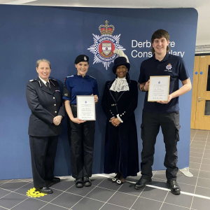 Male and female public service students holding a certificate stood by a female police officer and the High Sherrif of Derbyshire.